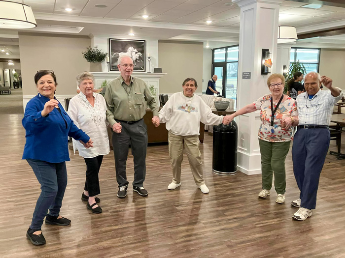 Senior resident smiling and waving, wearing a 'Strongsville Superstars' shirt, participating in a community event, capturing the joy and spirit of active senior living.
