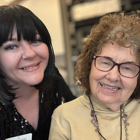 Team member and senior woman smile together at CedarStone Senior Living.