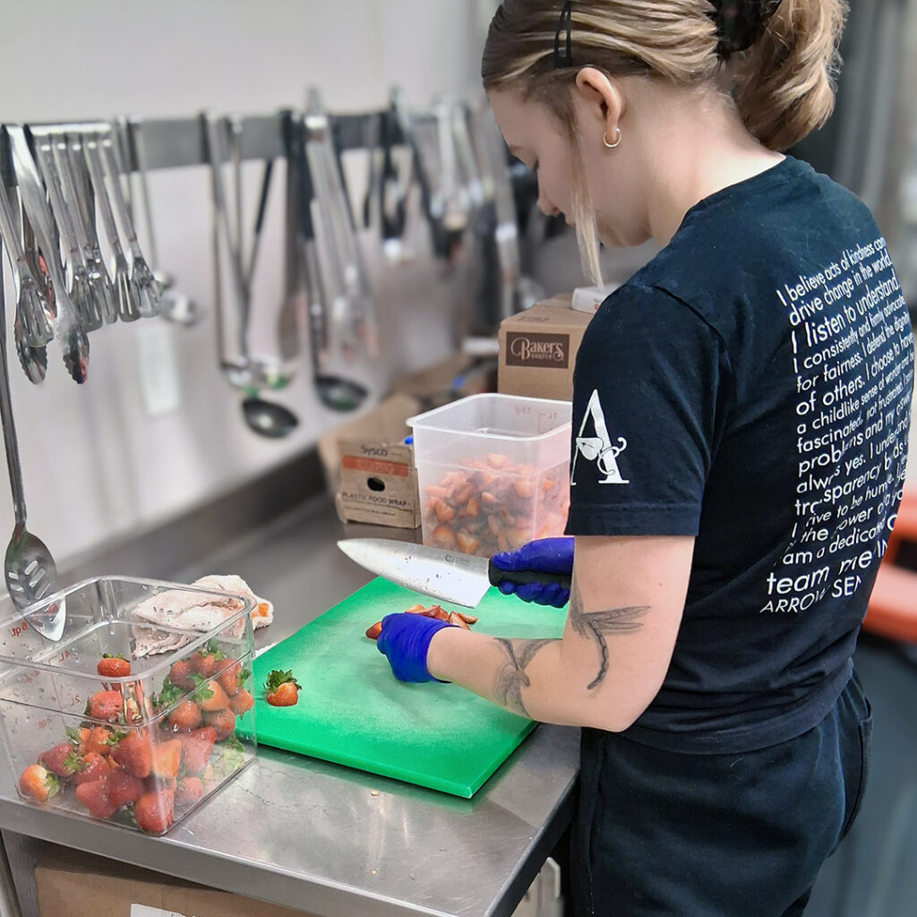A culinary team member prepares fresh strawberries at CedarStone Senior Living.